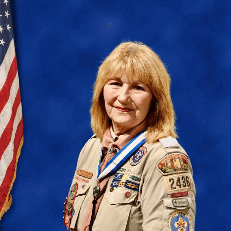 A person in a Boy Scouts of America uniform stands next to an American flag.