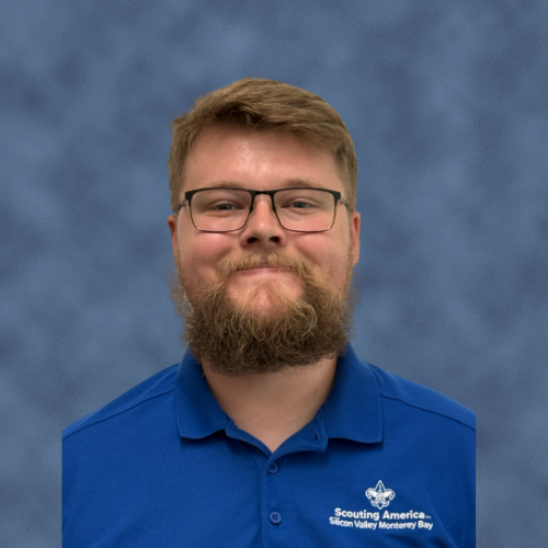 A person with a beard wearing glasses and a blue shirt with "Scouting America Silicon Valley Monterey Bay" text. Scout staff.