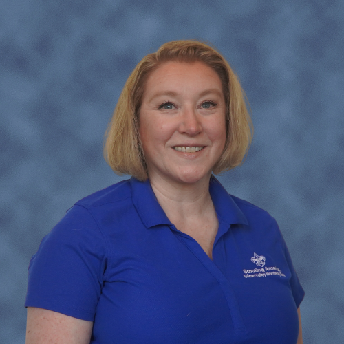 A person in a blue polo shirt with a scout logo and text is smiling at the camera.