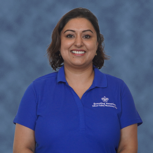 A person wearing a blue polo with "Scouting America" text, smiling against a blue background. The keyword "scout staff" is appropriate.