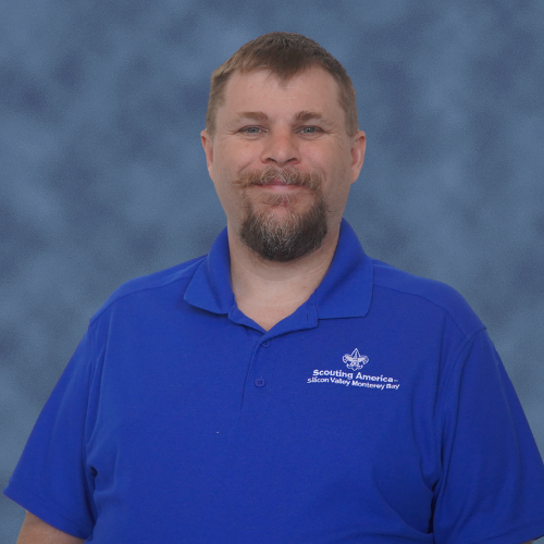 A person wearing a blue polo shirt with "Scouting America Silicon Valley Monterey Bay" logo, on a blue background.