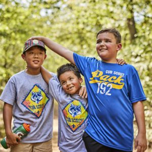 Three Cub Scouts supporting one another during an outdoor activity
